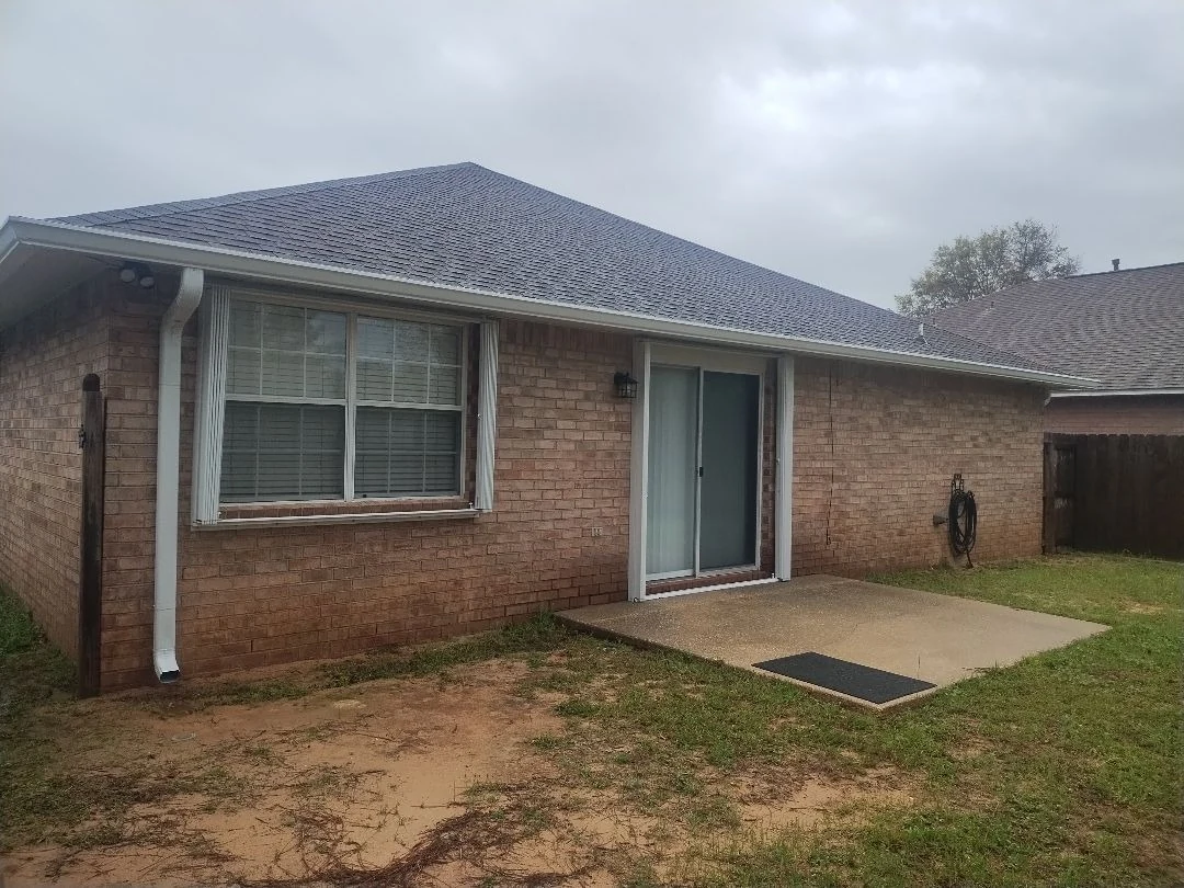 White downspout and seamless gutter on a brick home exterior.