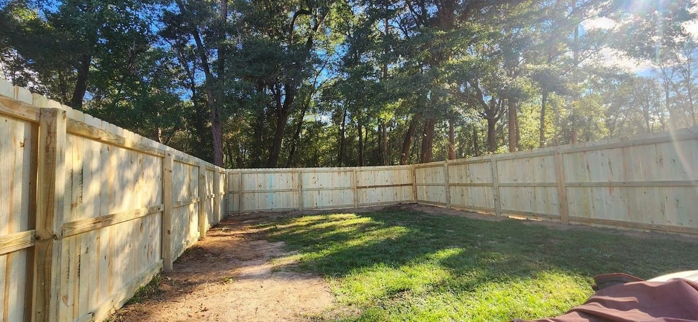Long new wood privacy fence running beside a residential property.