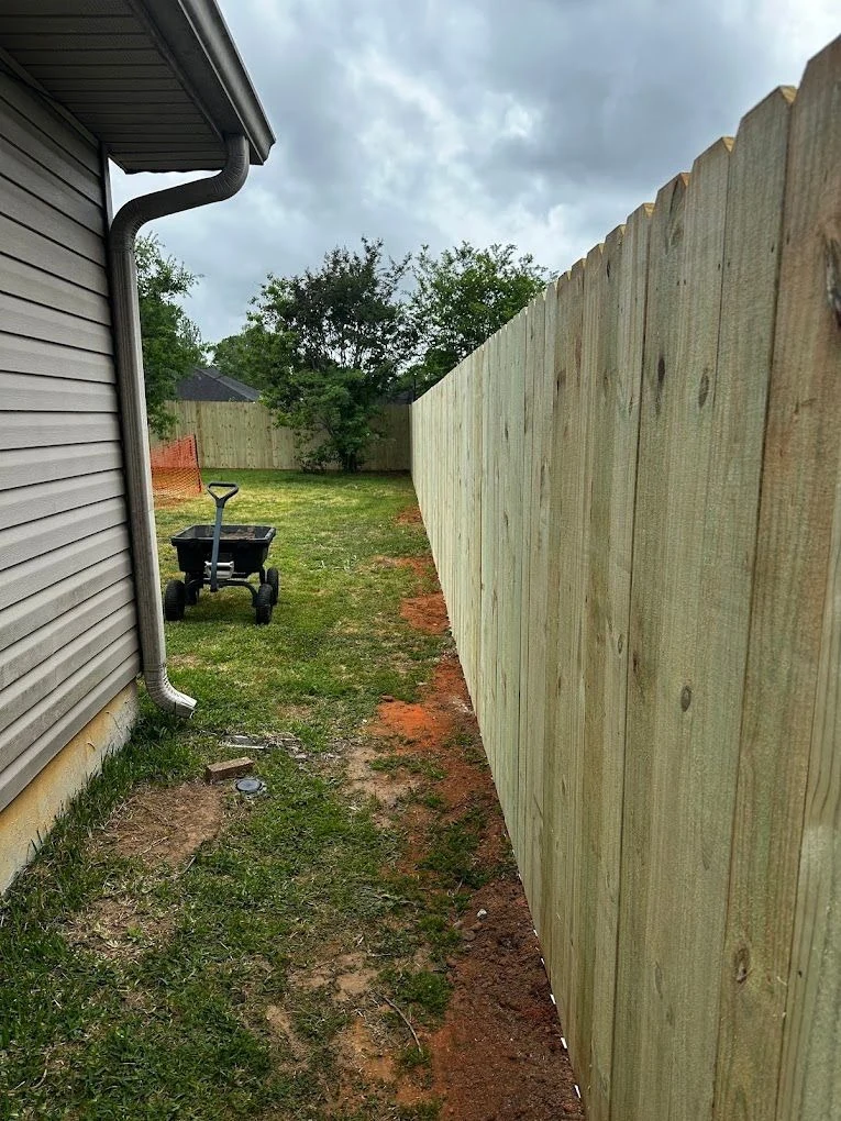 Wood privacy fence beside a house, vertical view.