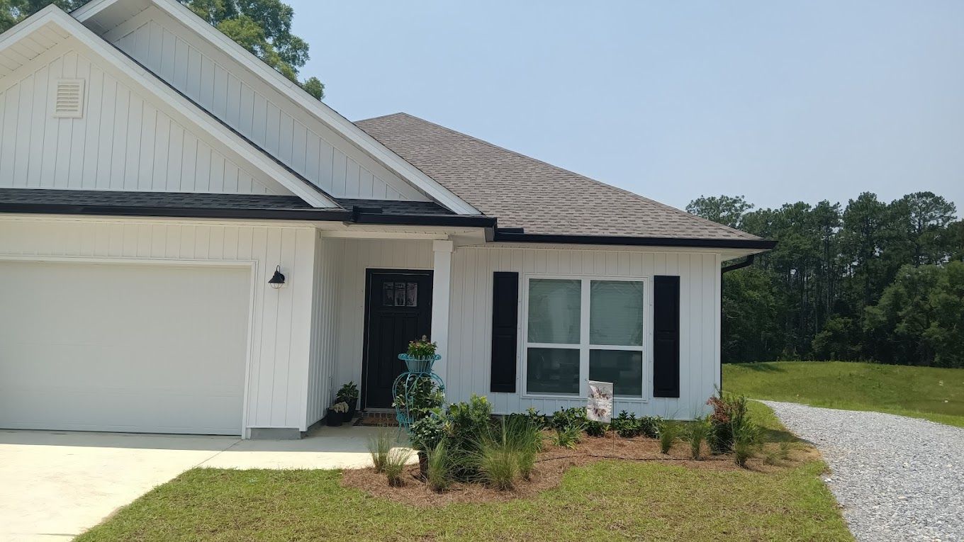 White single-story residence with dark seamless gutters and a downspout running along the roofline.