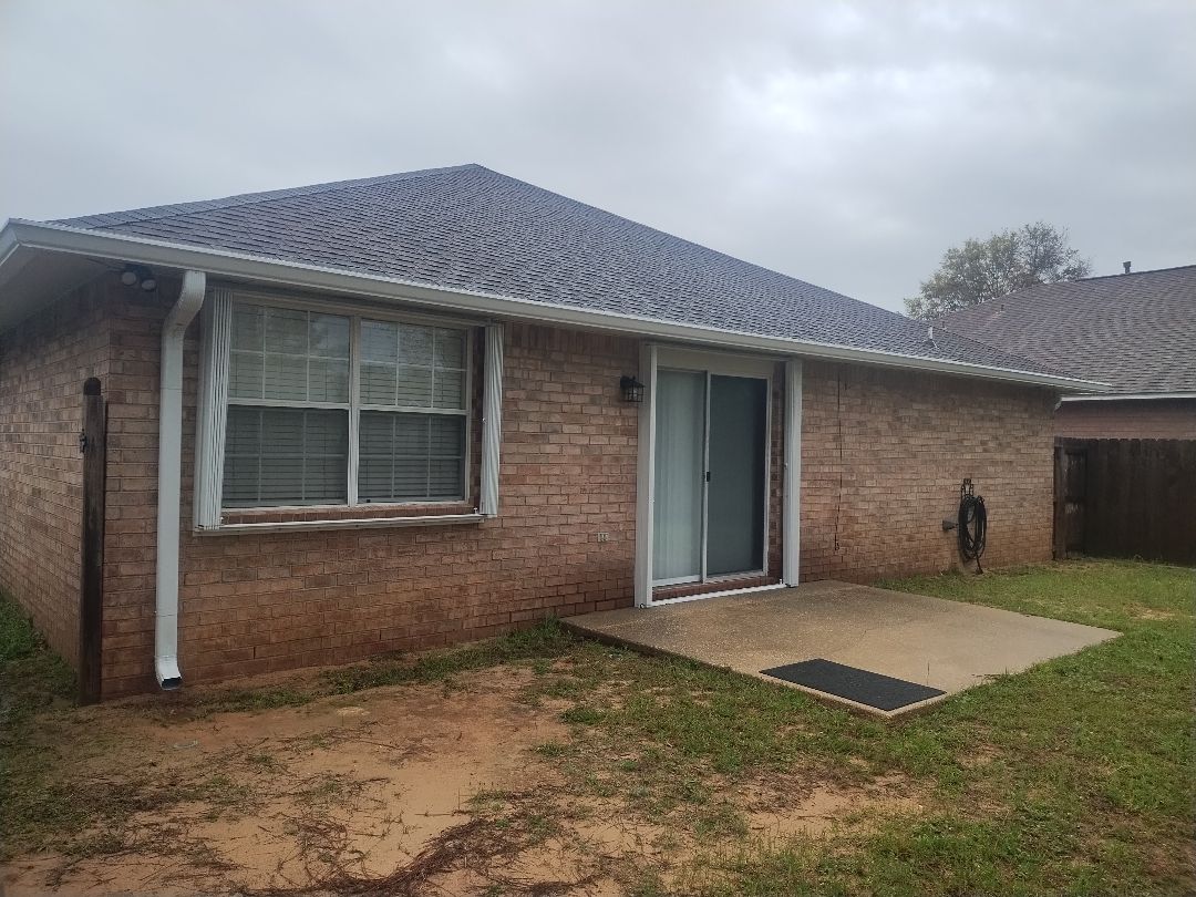White downspout and seamless gutter on a brick home exterior.
